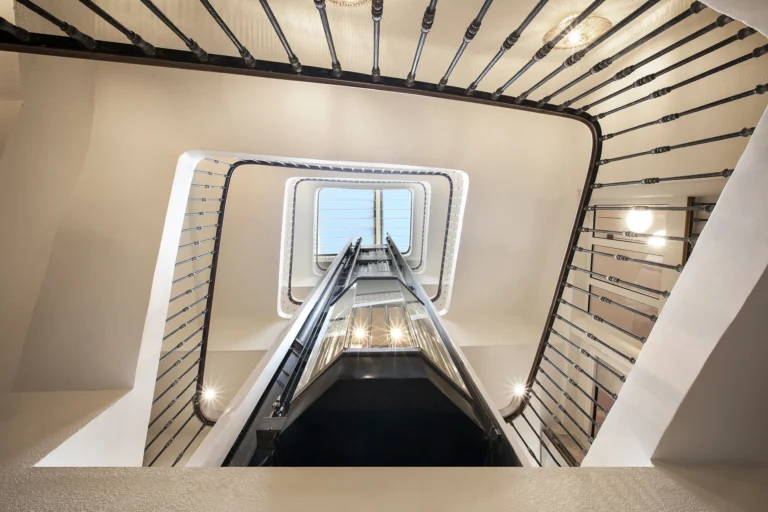 Photographie d’architecture en contre-plongée d’un escalier avec ascenseur vitré sous verrière, Life Hotel Marseille Vieux-Port, par Armando Garcia