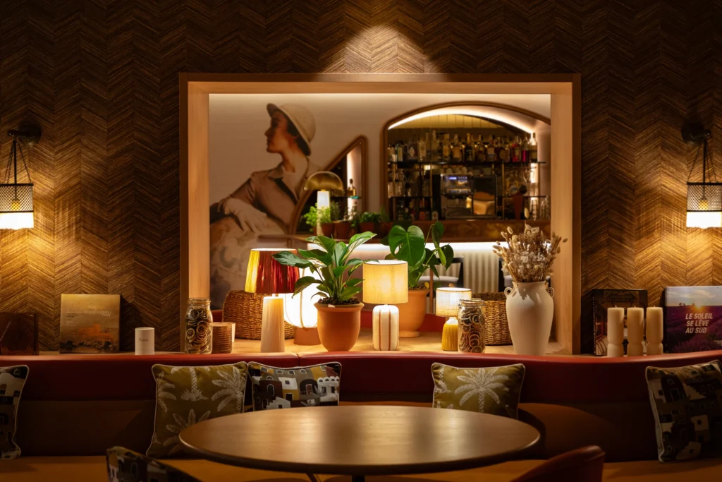 Photographie d’architecture du lounge de nuit de l’Hôtel Beauvau MGallery à Marseille, avec table, banquette, décoration lumineuse et bar en arrière-plan, par Armando Garcia