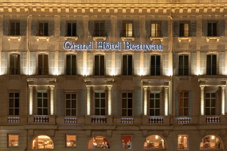Façade du Grand Hôtel Beauvau MGallery à Marseille de nuit, éclairage architectural et fenêtres alignées