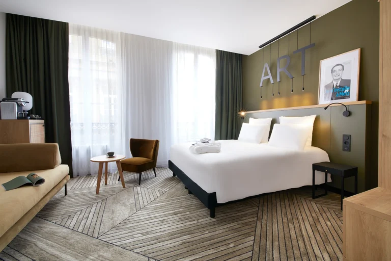 Photographie d’intérieur d’une chambre premium du Mercure Grand Hôtel Metz Centre Cathédrale, avec lit double, fauteuil, table basse et grande fenêtre en lumière naturelle, par Armando Garcia