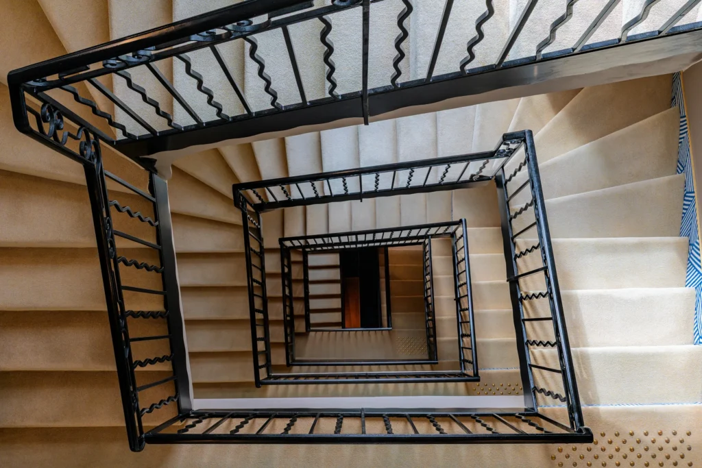 Photographie d’intérieur de l’escalier du Grand Hôtel Beauvau MGallery à Marseille, vue en perspective verticale avec lignes géométriques, par Armando Garcia